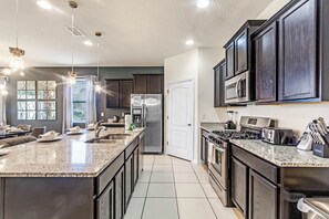 A modern kitchen with dark wood cabinets, stainless steel appliances, and a large island with a granite countertop.