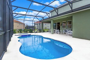 Piscina com cobertura de vidro, área de estar ao ar livre e vista para casas vizinhas.