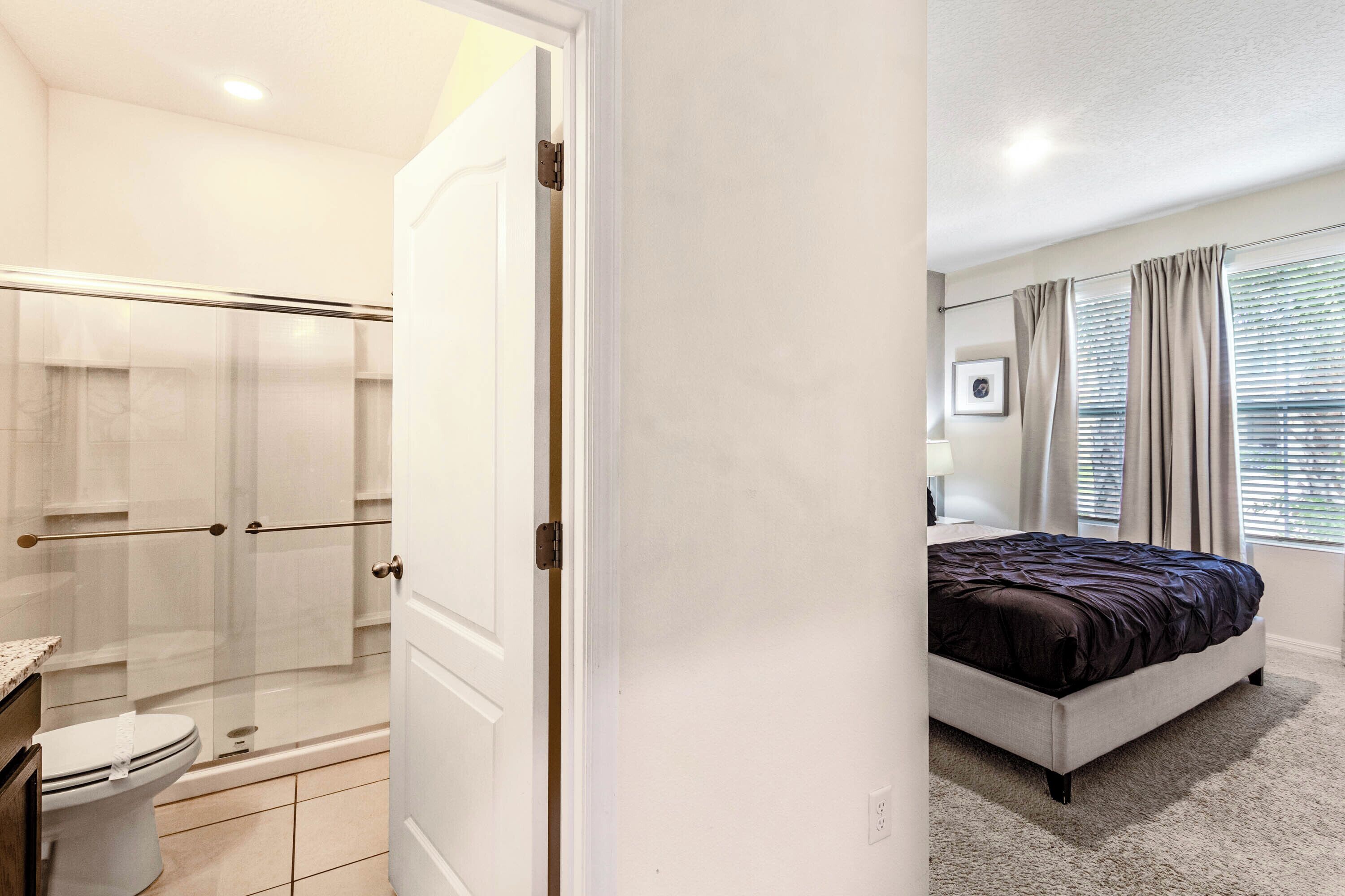 Een slaapkamer met een bed, een badkamer met douche en toilet.
