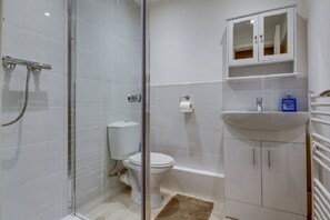 Ein Badezimmer mit Glasdusche, Toilette, Waschbecken und einem Spiegelkorpus.