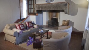 A cozy living room with a fireplace, a sofa, a chair, and a coffee table. - APARTMENT DELUXE (Pontassieve)