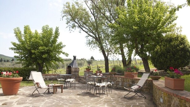 An outdoor patio with stone flooring, several lounge chairs, and a stone wall. - APARTMENT DELUXE (Pontassieve)