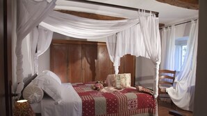 A bedroom with a canopy bed, wooden headboard, and a quilted bedspread. - APARTMENT DELUXE (Pontassieve)