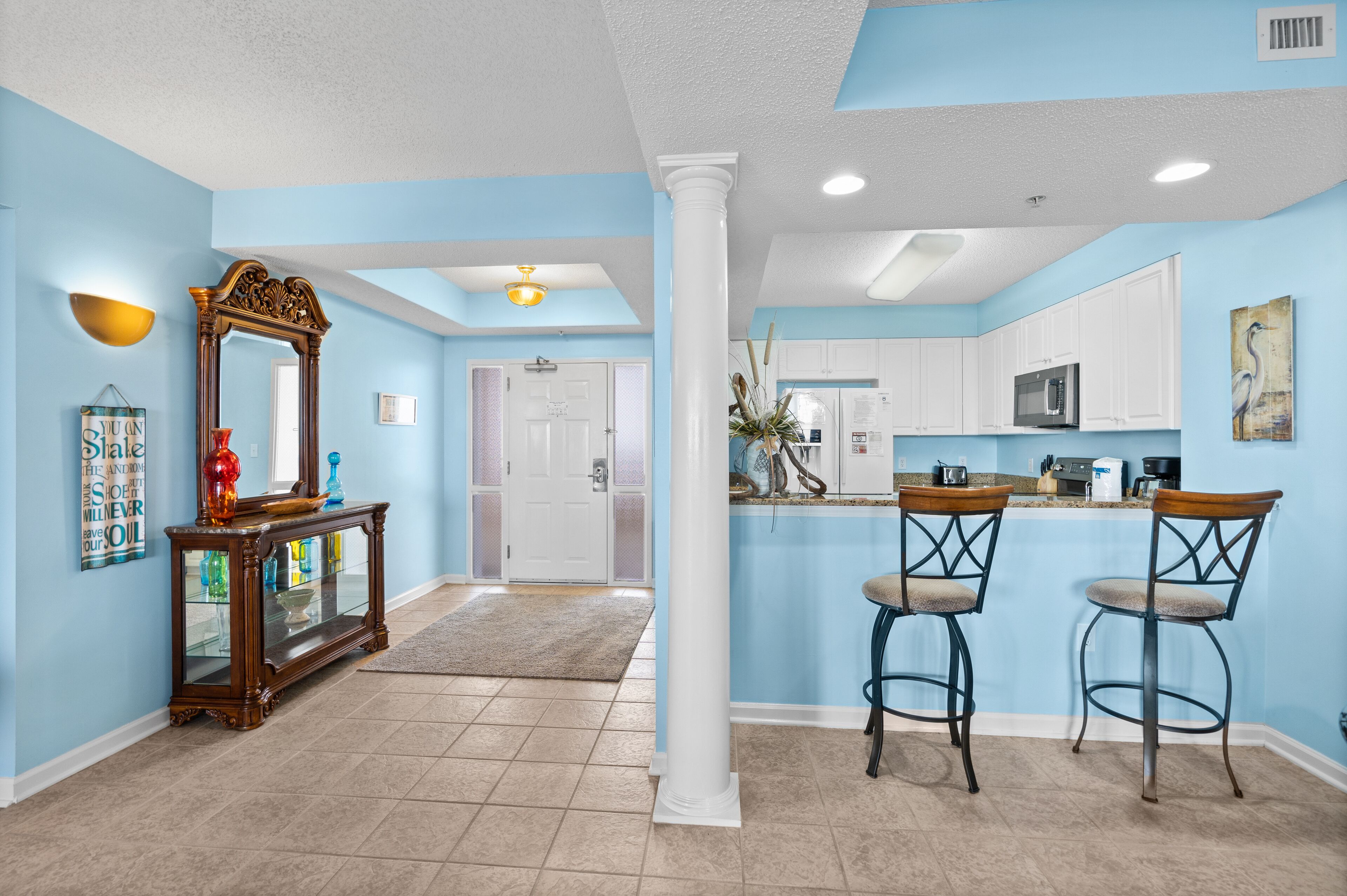 A modern kitchen with white cabinets, a microwave, and a coffee maker.