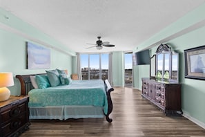 A bedroom with a bed, dresser, and a ceiling fan.
