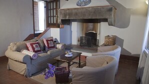 Un salon chaleureux avec une cheminée, un canapé, un fauteuil et une table basse.