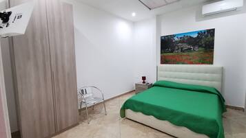 Une chambre à coucher comprenant un lit, une armoire, une chaise, une table de chevet et un climatiseur fixé au mur.