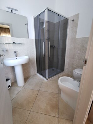 Ein modernes Badezimmer mit einer Duschkabine, einem Standwaschbecken und einer Toilette.