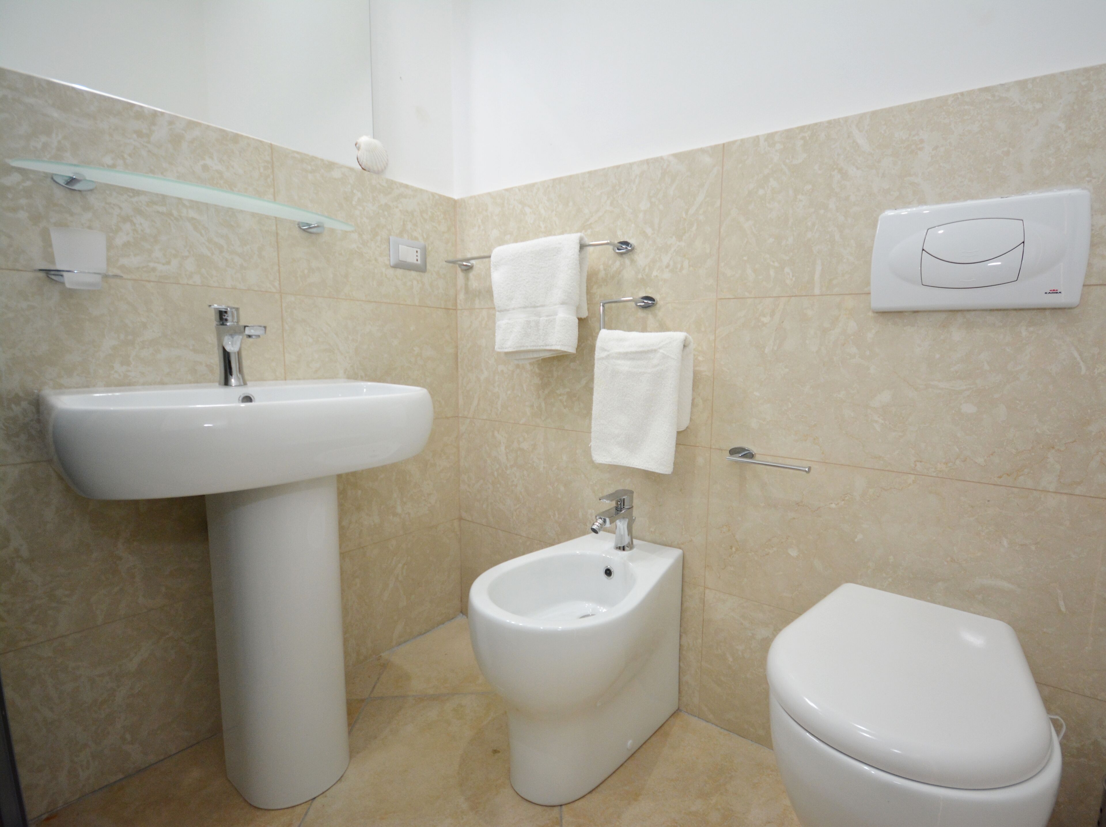 A bathroom with a pedestal sink, a bidet, and a toilet.