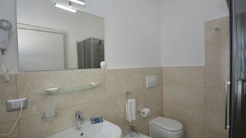 Een moderne badkamer met een wastafel, toilet, bidet en een glazen plank.