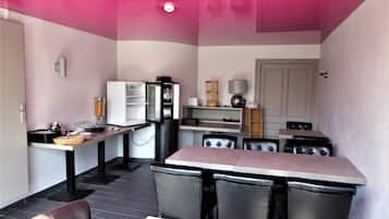 A compact kitchen with a refrigerator, microwave, and dining area with chairs and a table.