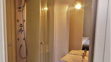A modern bathroom with a glass-enclosed shower, a sink, and a mirror.