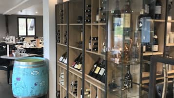 A wine cellar with glass shelves displaying various bottles and a large barrel with a map design.