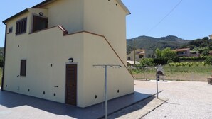 Un edificio de dos pisos con techo inclinado, un pequeño balcón y una puerta con un ventanal encima.