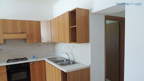Una cocina con armarios de madera, estufa a gas, horno, lavaplatos y salpicadero de azulejos.
