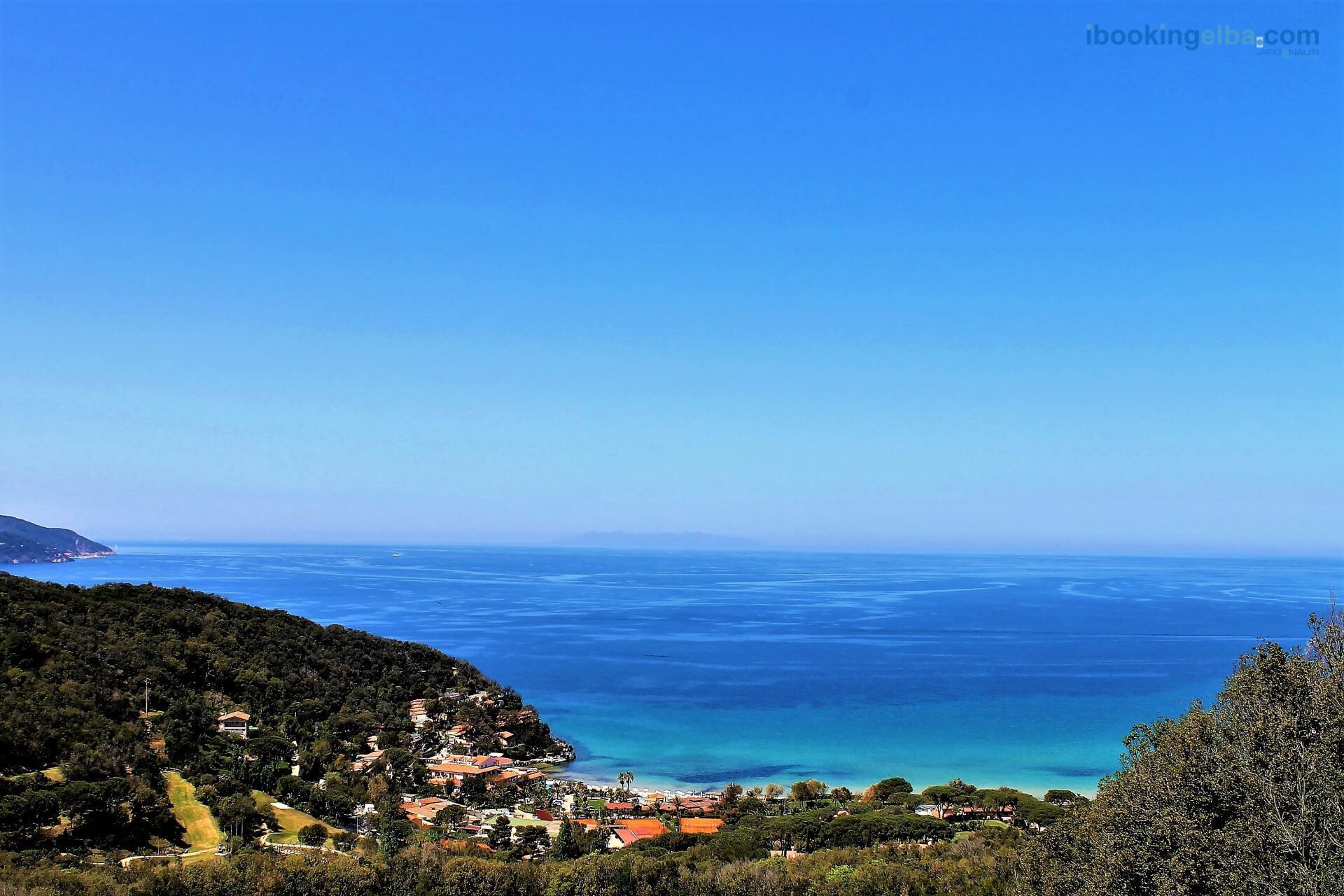 A coastal town with buildings on a hillside overlooking the sea.