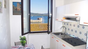 A kitchen with a view of the sea, a window, and a small table with a plant. - Cosmopolis (Portoferraio)