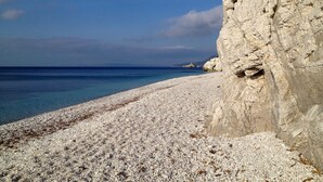 A pebble beach with a rocky cliff and calm sea. - Cosmopolis (Portoferraio)
