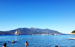 A coastal scene with boats and mountains in the background. - Villa Enfola (Portoferraio)