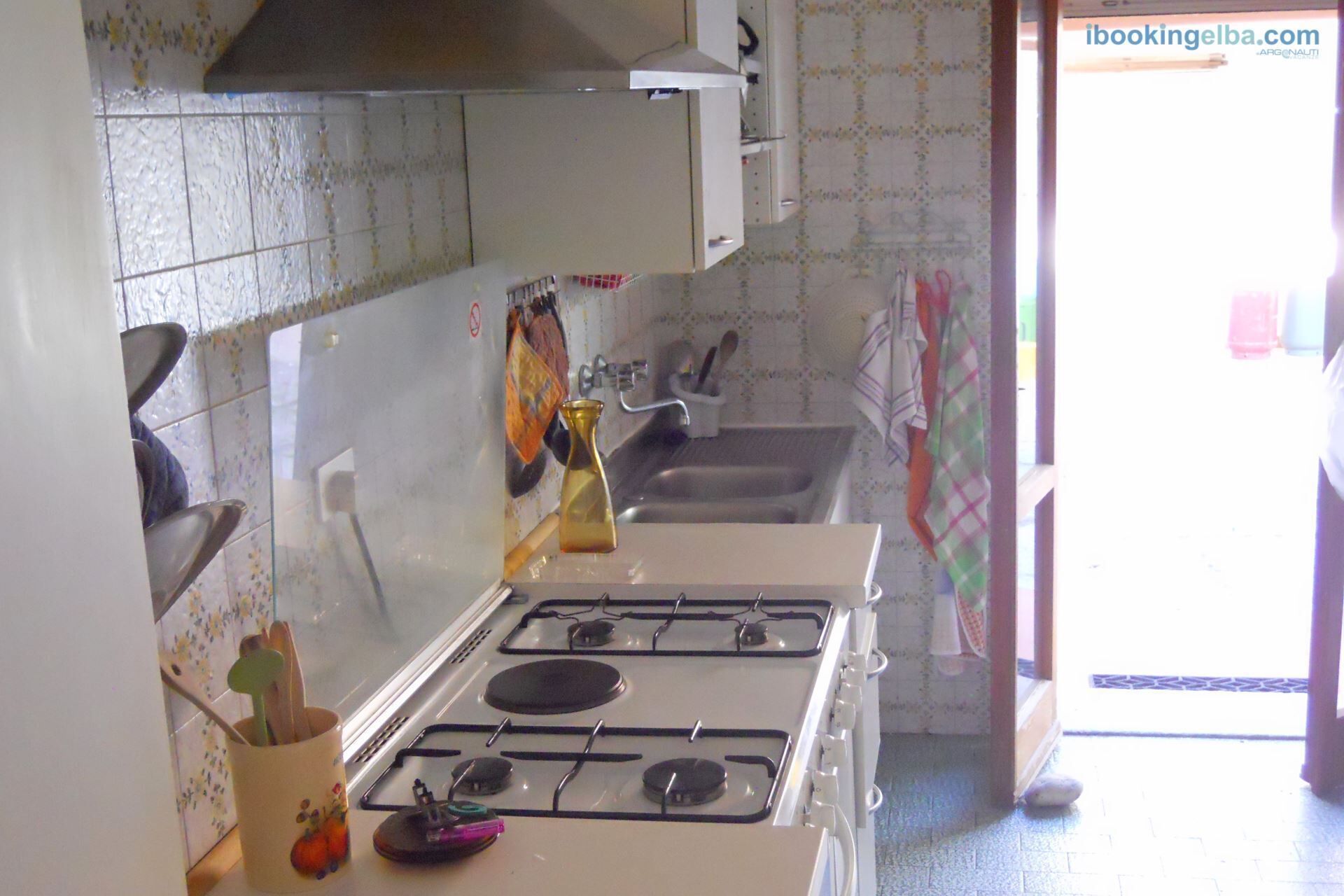 Una cocina con estufa, lavamanos y salpicadero de azulejos.