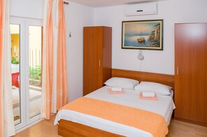 Quarto com cama, guarda-roupa, quadro e porta de correr para o exterior.