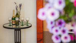 Une table ronde avec deux bouteilles de vin, deux verres à vin et un vase de lavande.