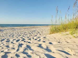 A sandy beach with footprints and tall grass in the foreground. - Watch Dolphins From Your Lanai, Sanibel Siesta Unit #601 (Sanibel)