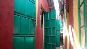 A narrow alleyway with green doors and red walls. - Eagles Lodge (Naivasha)