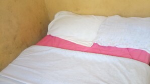 A bed with white and pink bedding in a room with yellow walls. - Eagles Lodge (Naivasha)
