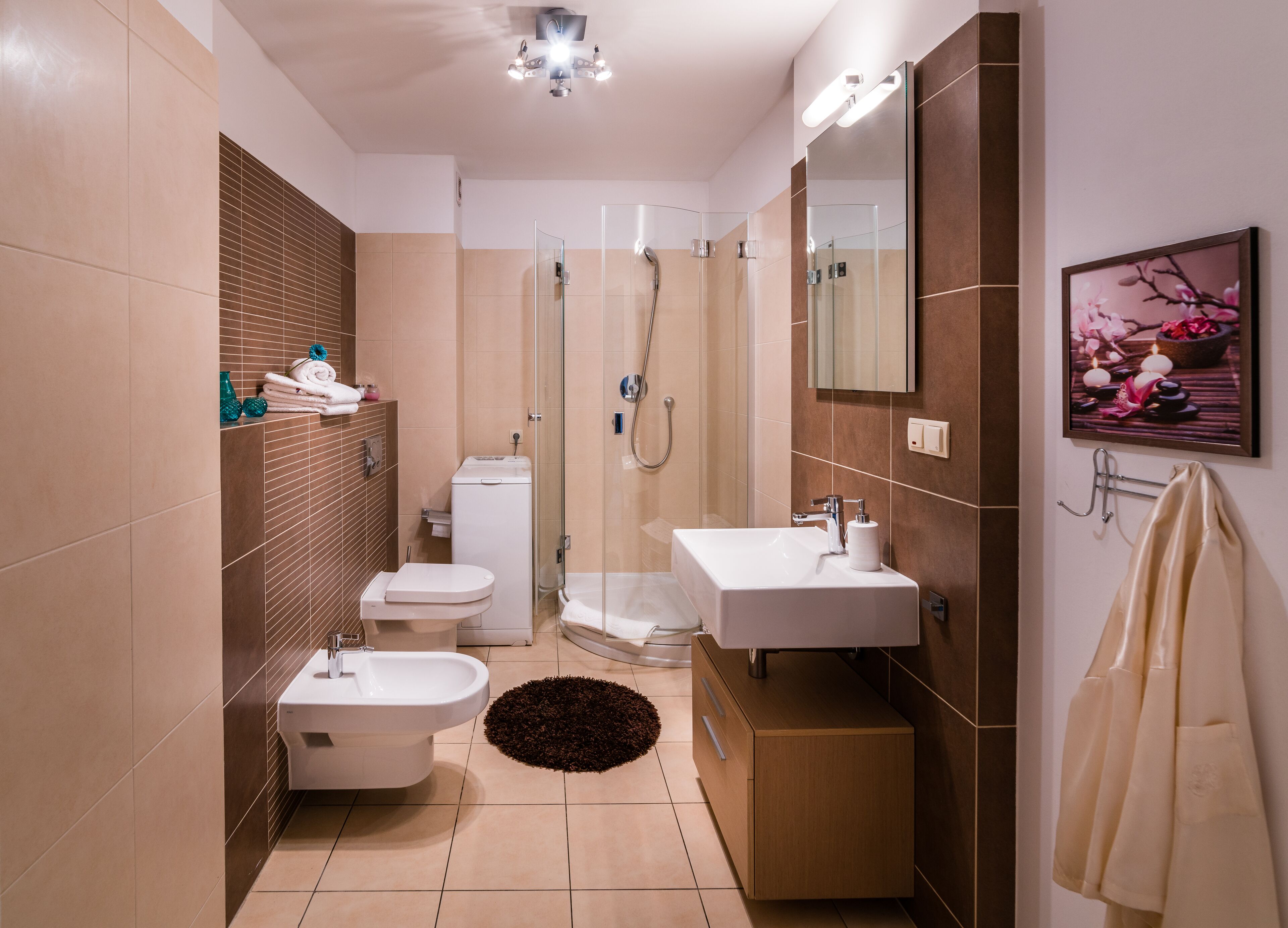 Et moderne badeværelse med bruser, toilet, bidet og håndvask.