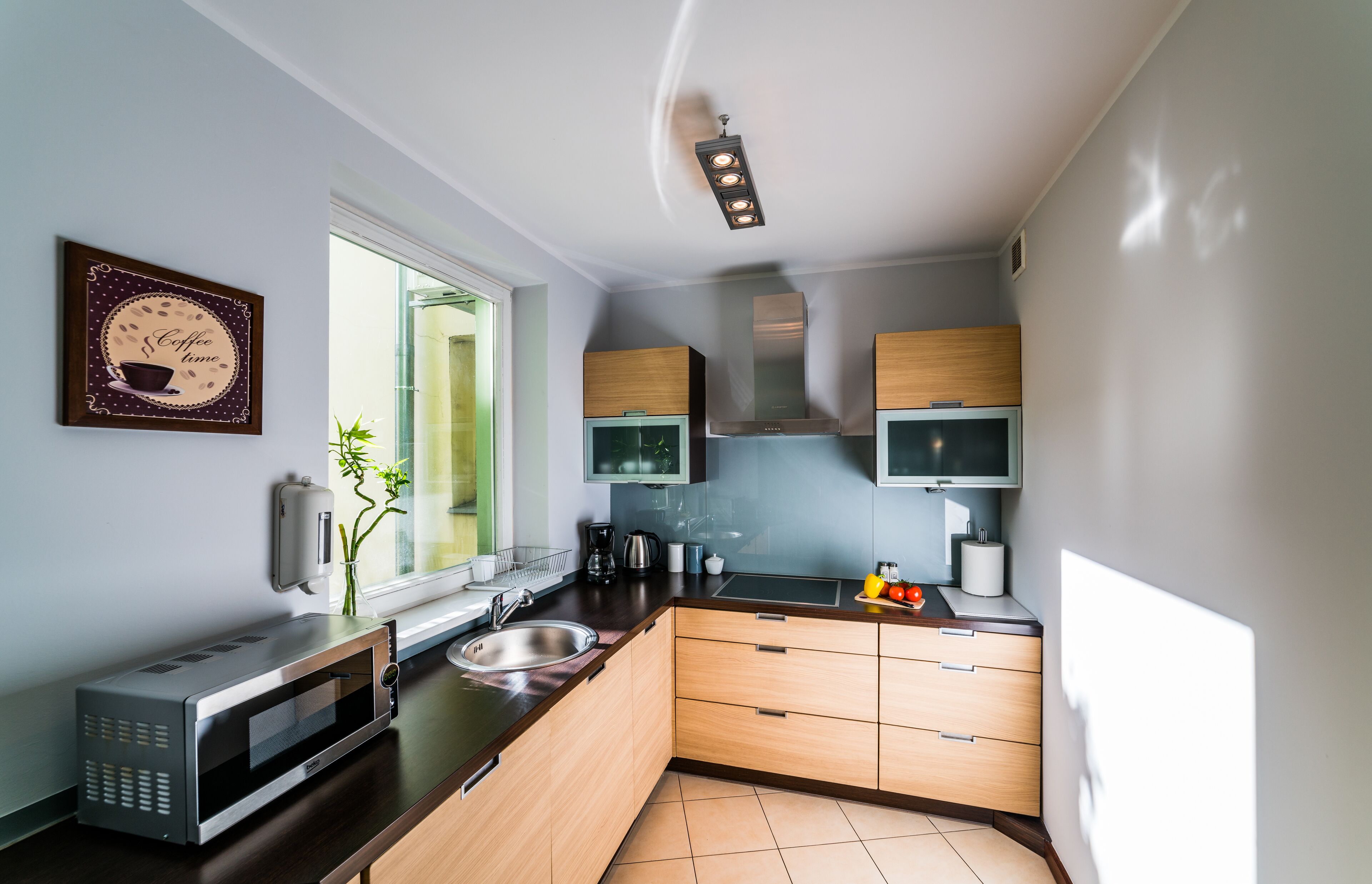A modern kitchen with a microwave, sink, and wooden cabinets.