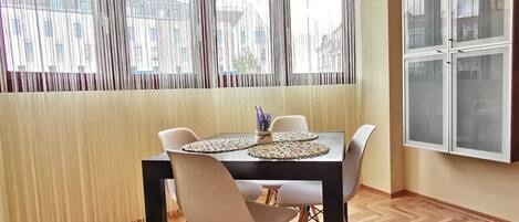 Een eetgedeelte met een tafel, stoelen, een hanglamp en een raam met gordijnen.
