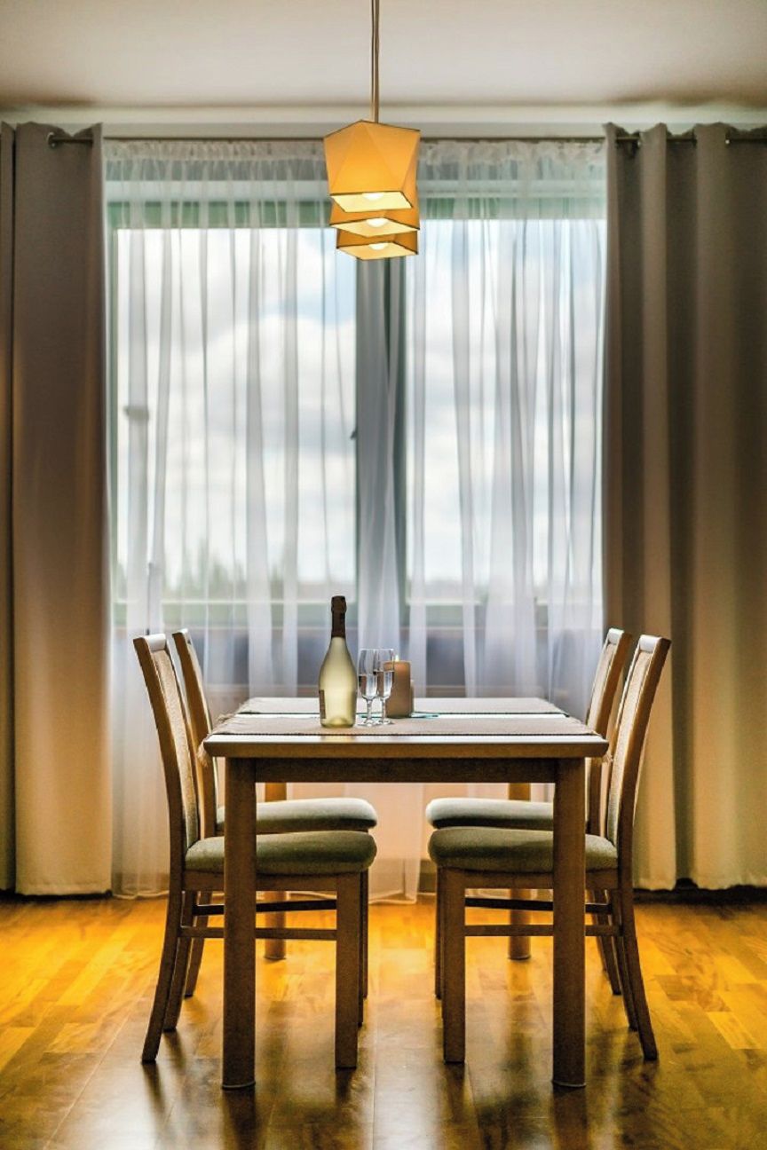 Et spiseområde med et bord, stole, en flaske, glas og en pendel.