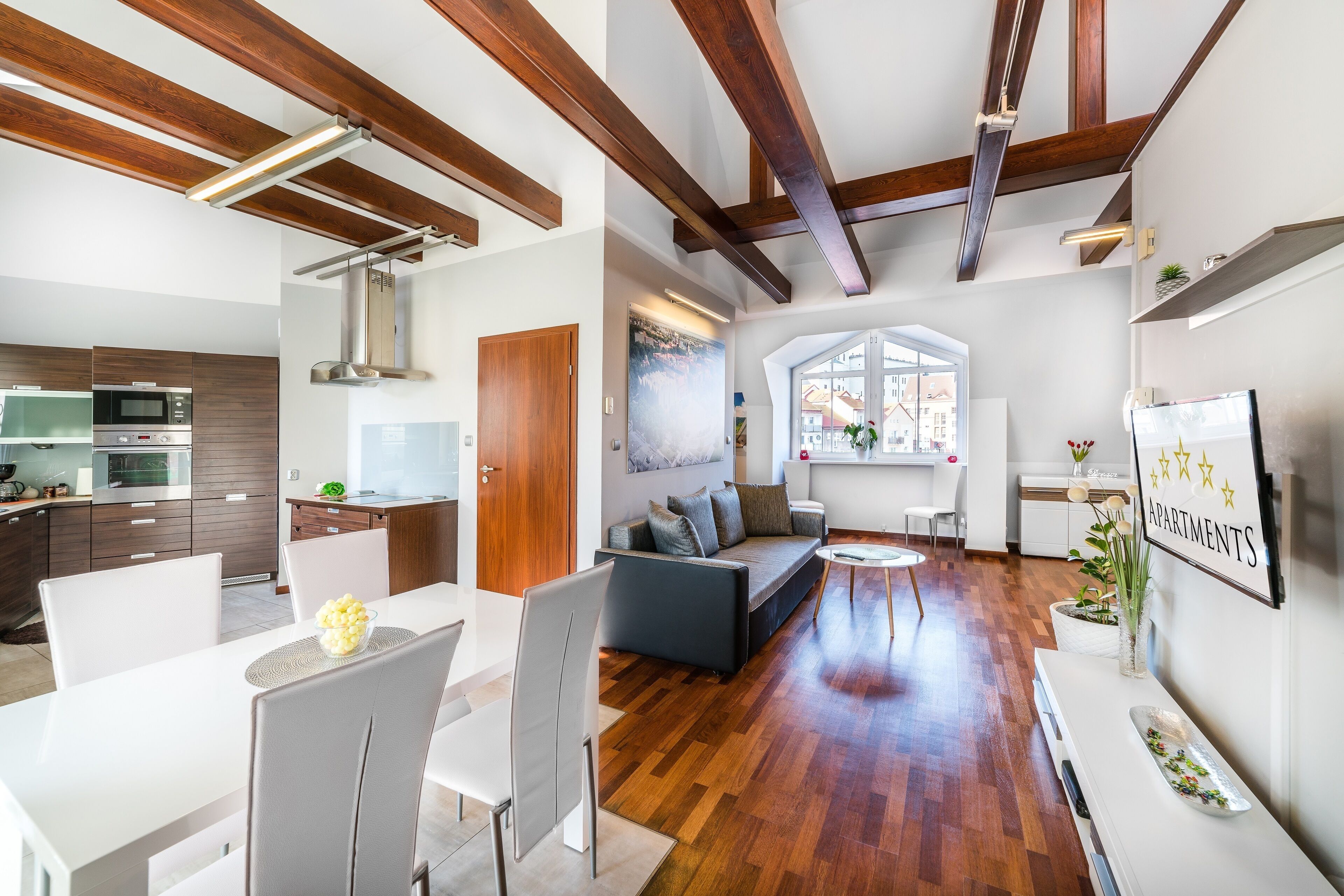 Una cocina moderna con electrodomésticos integrados, un comedor con mobiliario blanco y una sala de estar con sofá y mesa de centro.