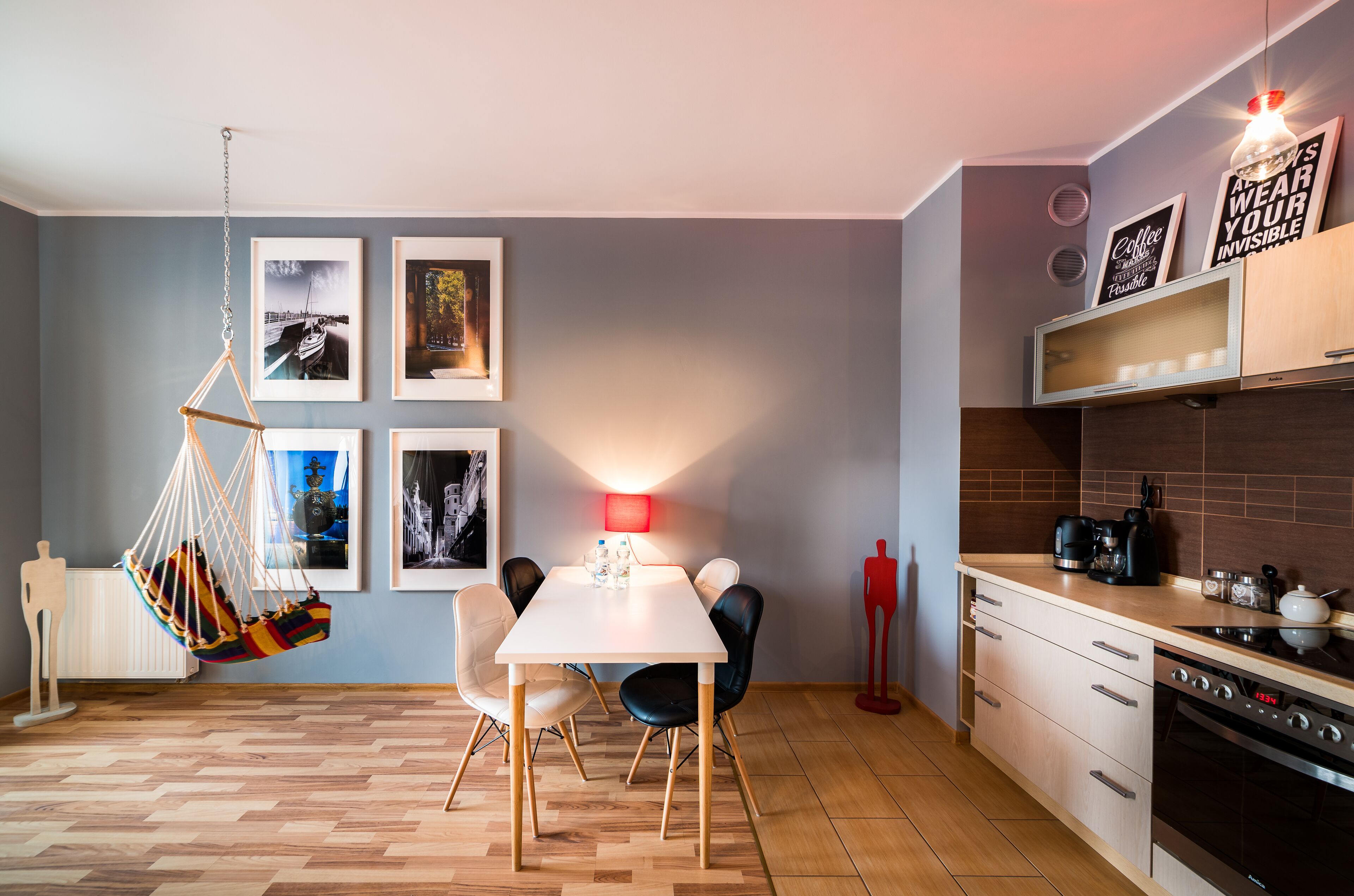 Una cocina moderna con comedor, que incluye un sillón colgante, una mesa con sillas y una lámpara roja.