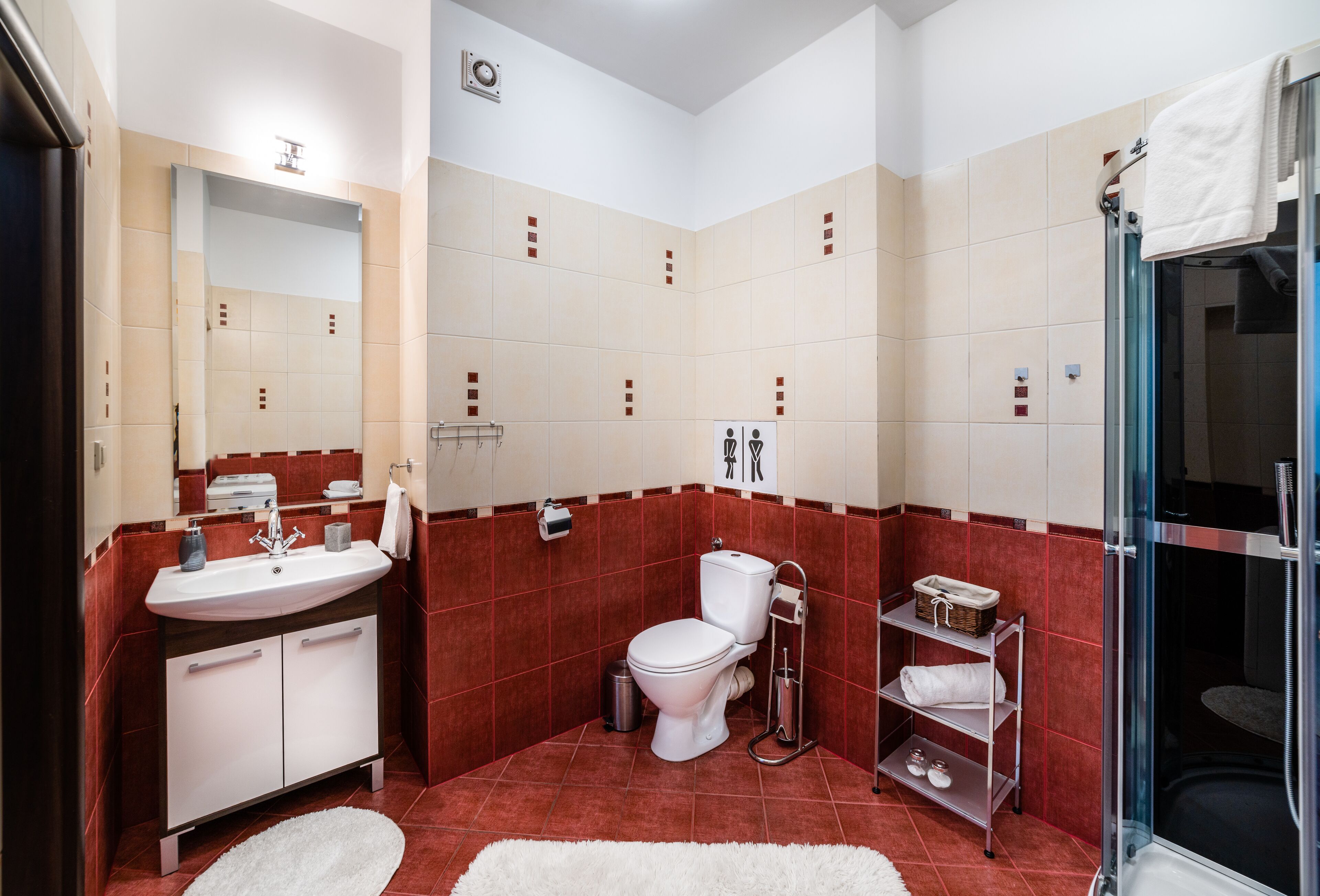 Un baño moderno con lavamanos blanco, inodoro, cabina de ducha de vidrio y un perchero para toallas.
