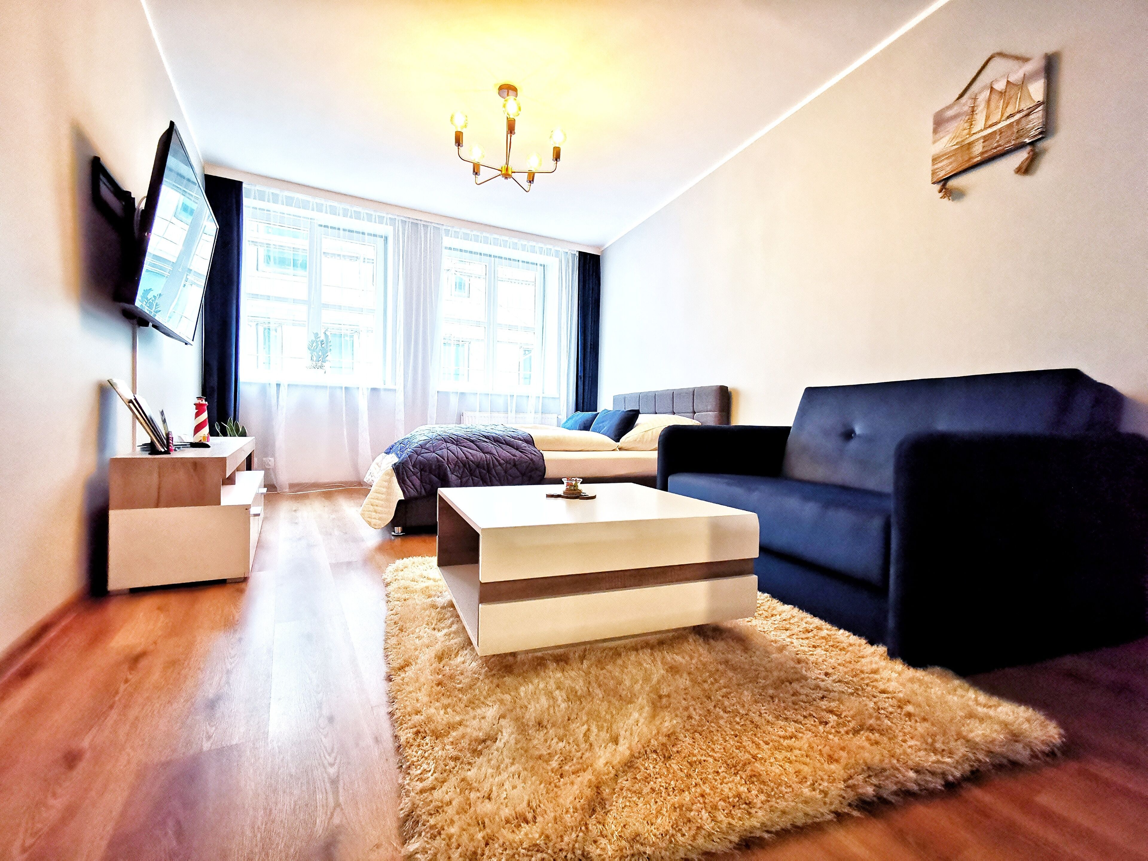 A modern living room with a sofa, a coffee table, and a TV mounted on the wall.