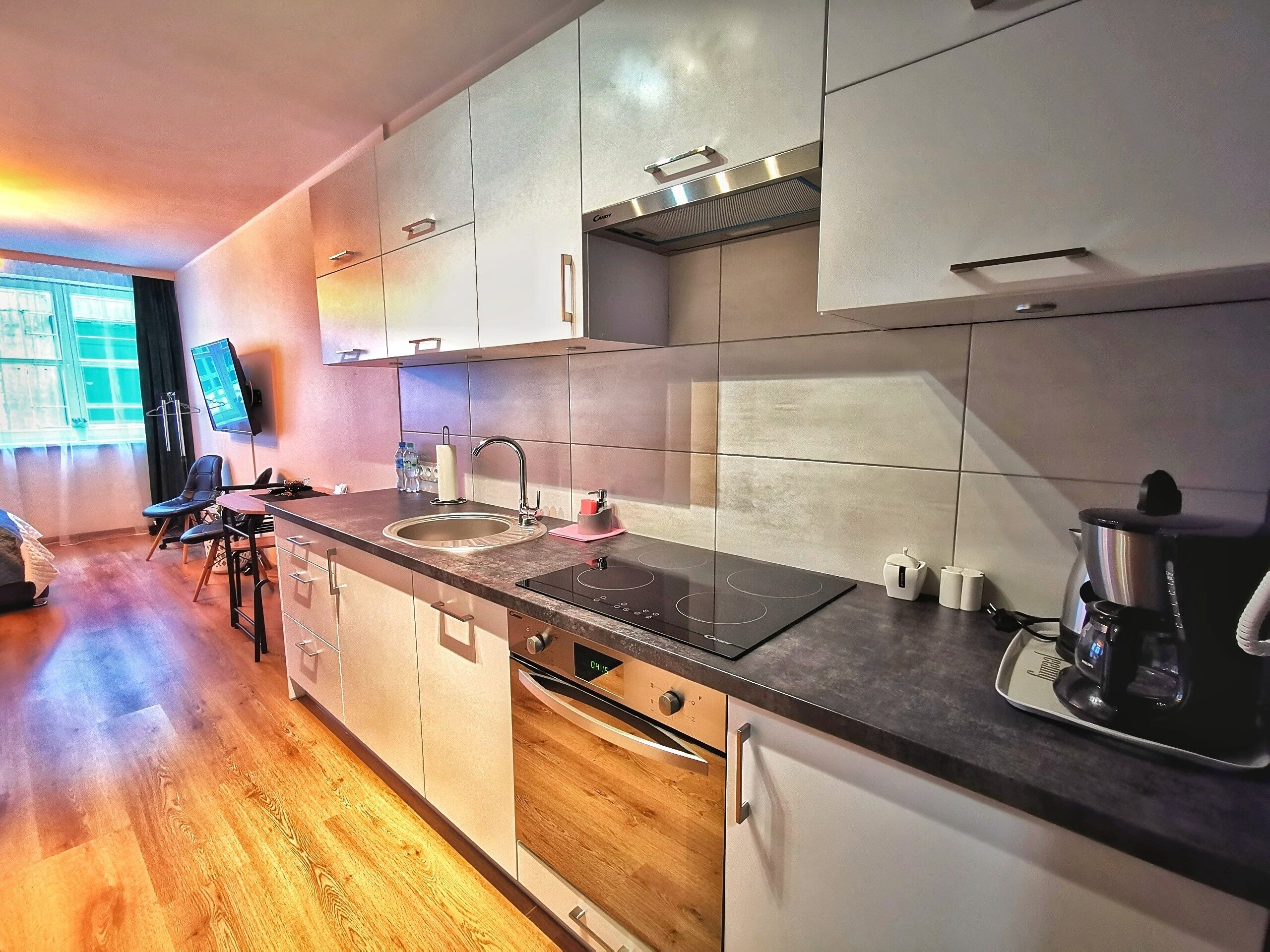 A modern kitchen with a built-in oven, a sink, and a coffee maker.