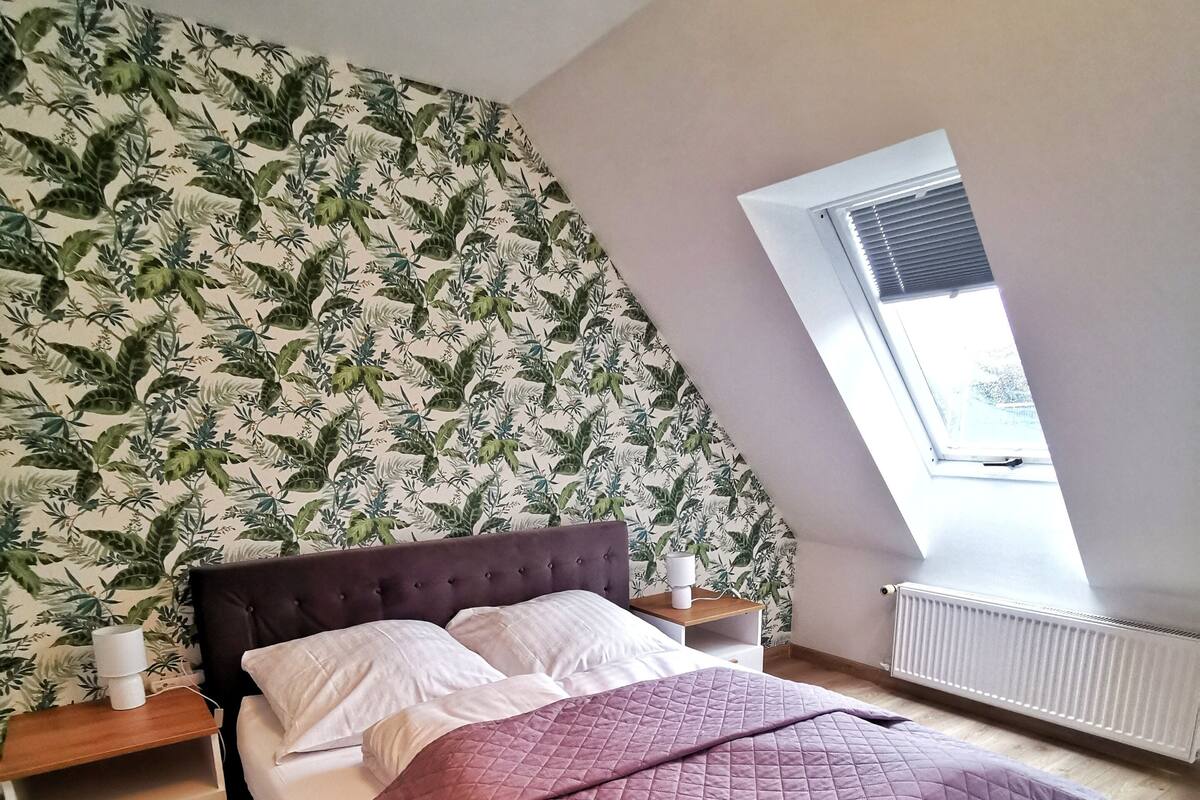 Une chambre à coucher avec un lit, une table de chevet, une fenêtre et un radiateur.