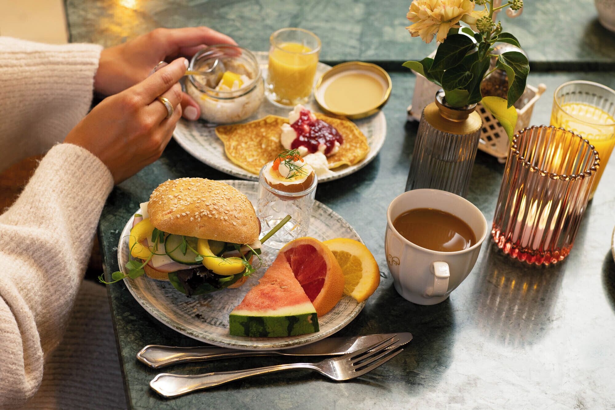 A breakfast setting with a plate of food, a cup of coffee, and a glass of orange juice.