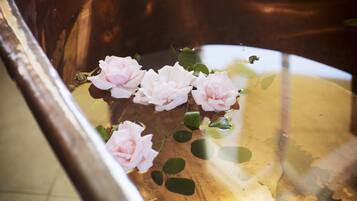 A copper bathtub with pink roses floating in water.