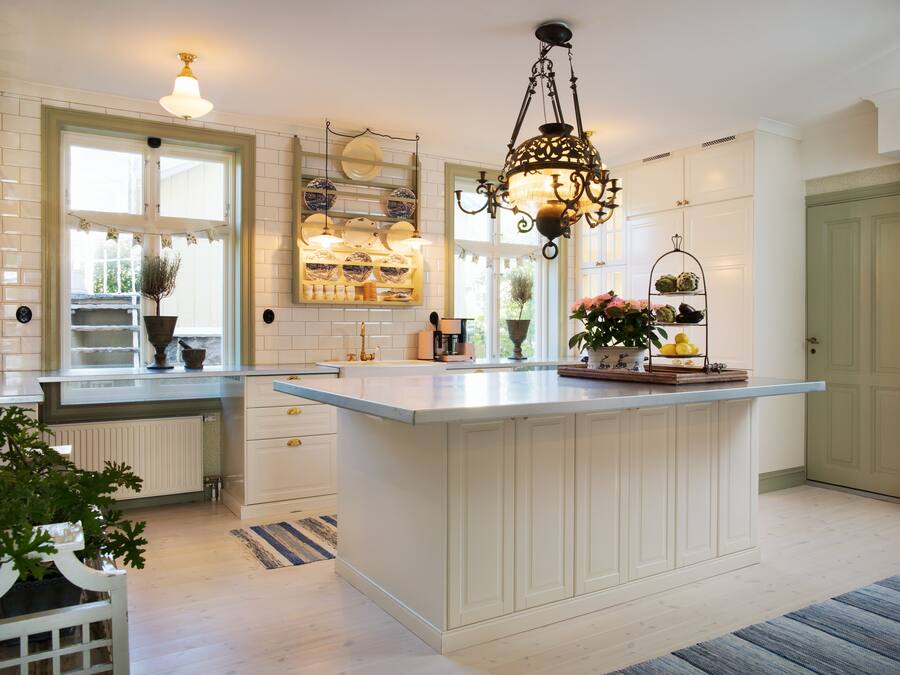 A spacious kitchen with a large island, white cabinetry, and a hanging light fixture.