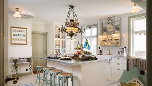 A kitchen with a central island, bar stools, a hanging light fixture, and a small model house. - Strandflickornas Annex Gula Villan (Lysekil)