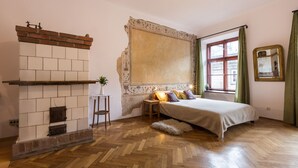 Une chambre avec une cheminée, un lit, une fenêtre avec des rideaux et un miroir au mur.