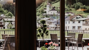 A terrace with outdoor seating and a view of a village with traditional houses and a church. - Appartement-Pension Kendlbacher (Grossarl)