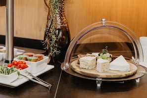 A buffet table with various cheeses, grapes, and condiments.
