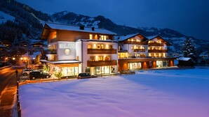 A multi-story hotel with a ski resort sign, surrounded by snow-covered mountains. - Appartement-Pension Kendlbacher (Grossarl)