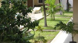 A hotel corridor with a tiled floor, palm trees, and a view of the outdoor area. - Girasoli Hotel (Malindi)
