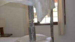 A single bed with a canopy in a room with a window. - Girasoli Hotel (Malindi)