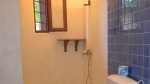 A bathroom with a shower, toilet, and a small shelf above the mirror. - Girasoli Hotel (Malindi)